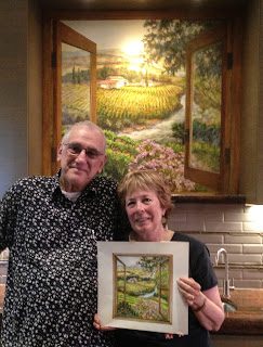 Couple holding framed landscape painting