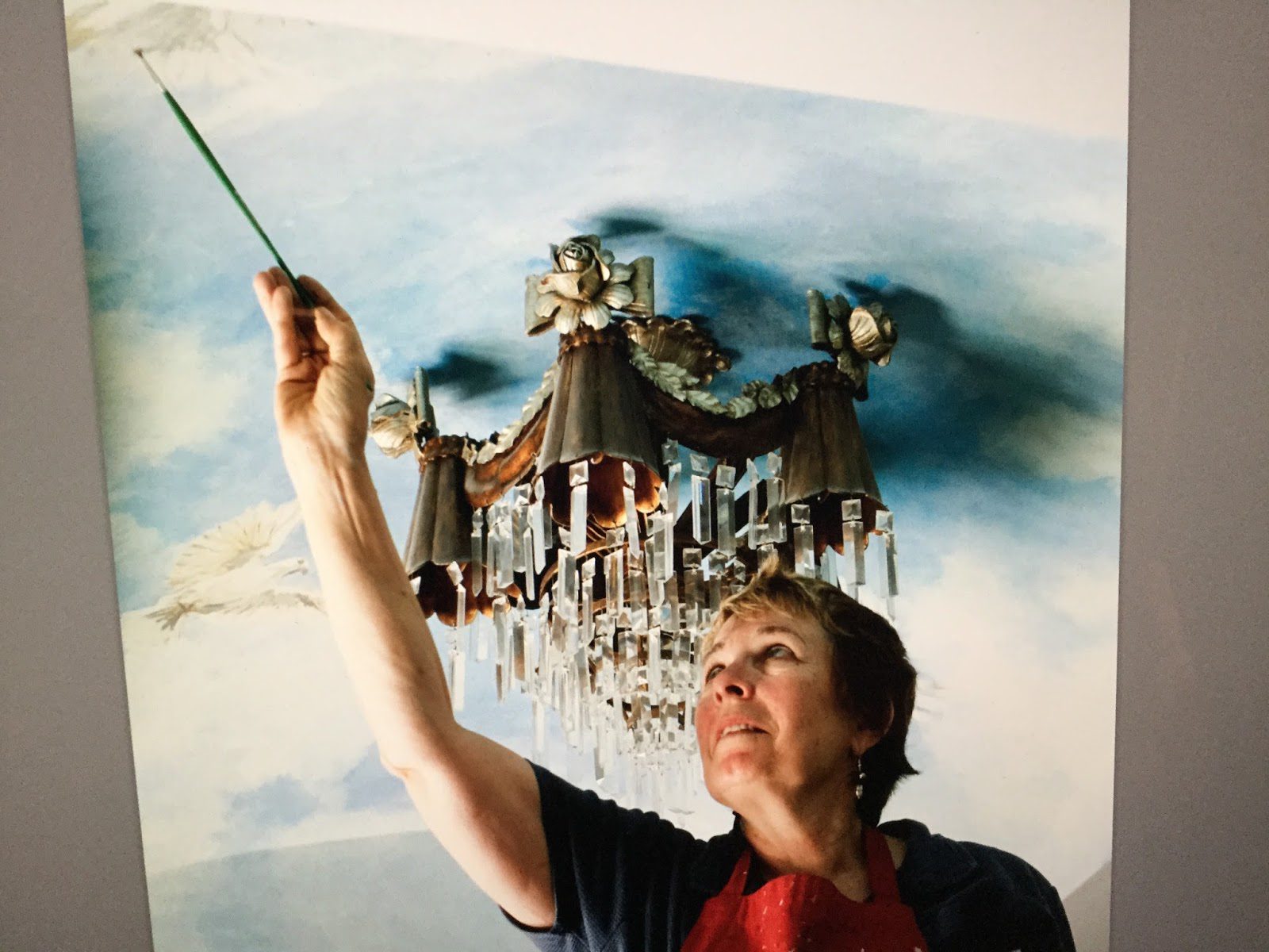 Woman painting sky-themed ceiling artwork
