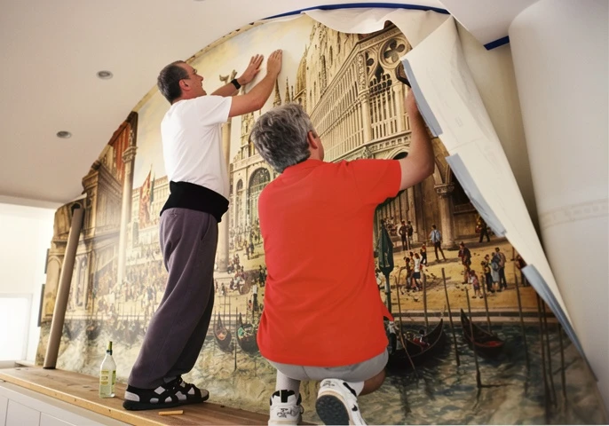 Two men installing large Venetian mural wallpaper
