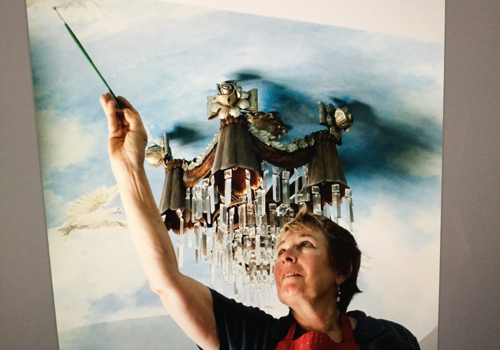 Woman painting sky-themed ceiling artwork